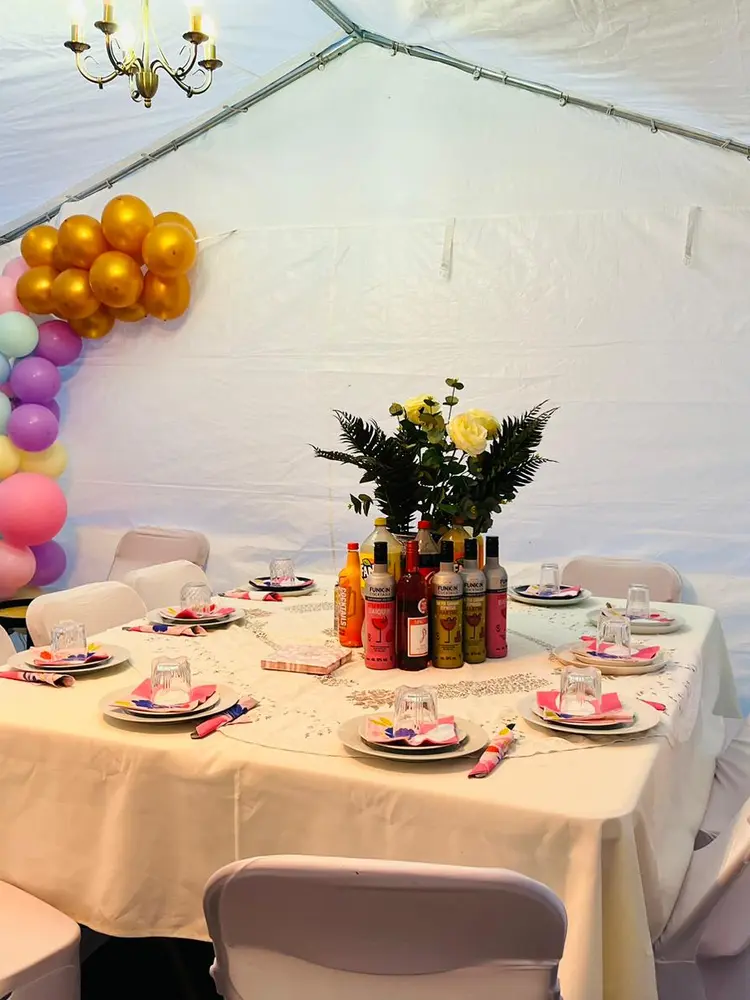 Round table set for a birthday inside a marquee with a gold and pastel balloon garland