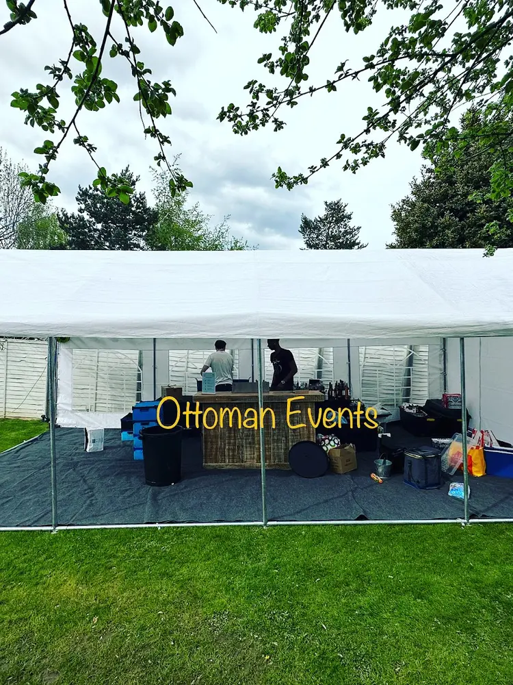 Open-sided white marquee on grass with a bar being set up inside