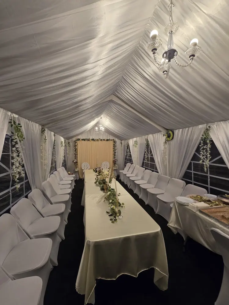 Marquee lined with white drapes and chandeliers, laid up for a wedding meal